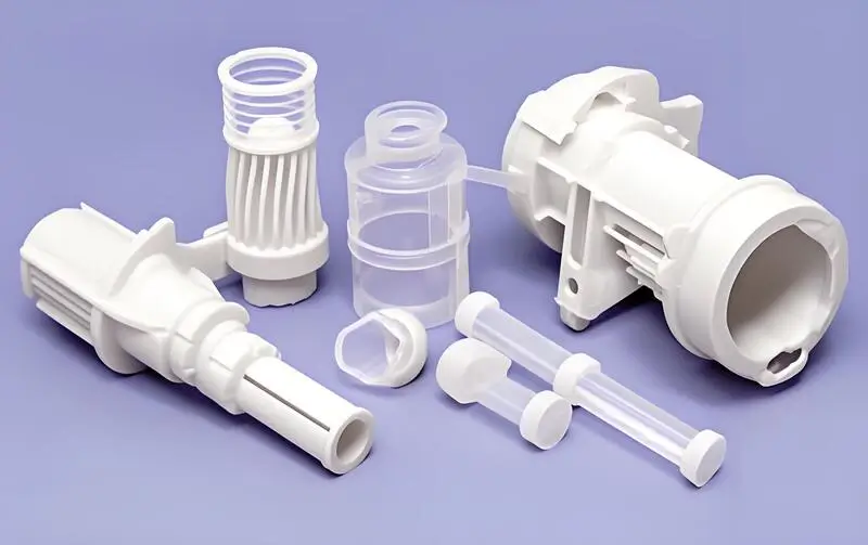 Pezzi assortiti in plastica bianca stampata a iniezione disposti su una superficie viola