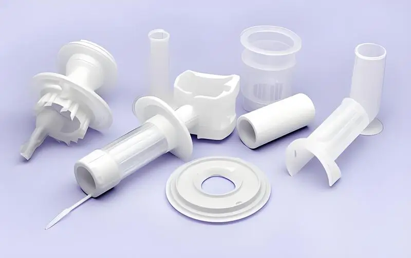 Diverses pièces moulées par injection en plastique blanc sur fond violet.