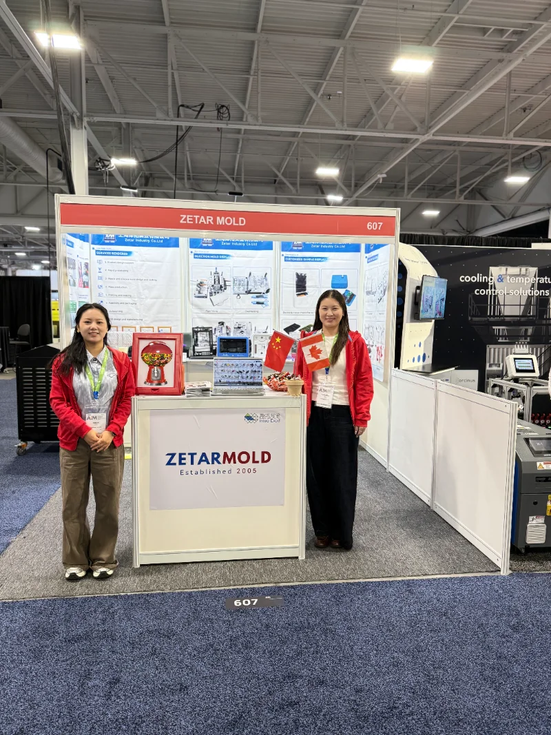 Display booth of Zetar Mold featuring informational posters and flags at a trade show with industrial exhibition setup.