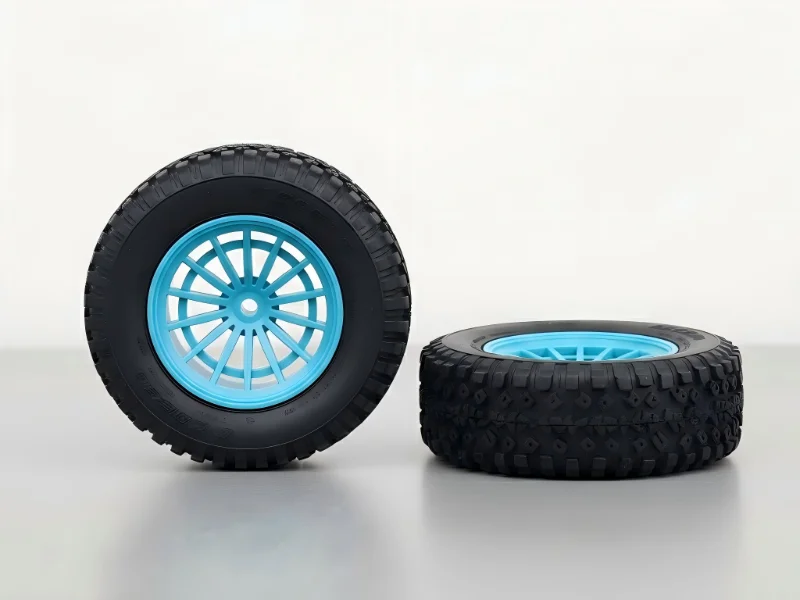 Two black tires with blue rims, one upright and one on its side, on a gray surface.