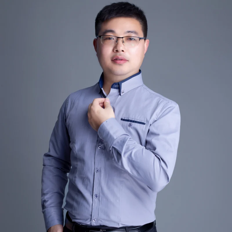 Man wearing a grey smart casual shirt with a blue trim collar, adjusting cuffs.