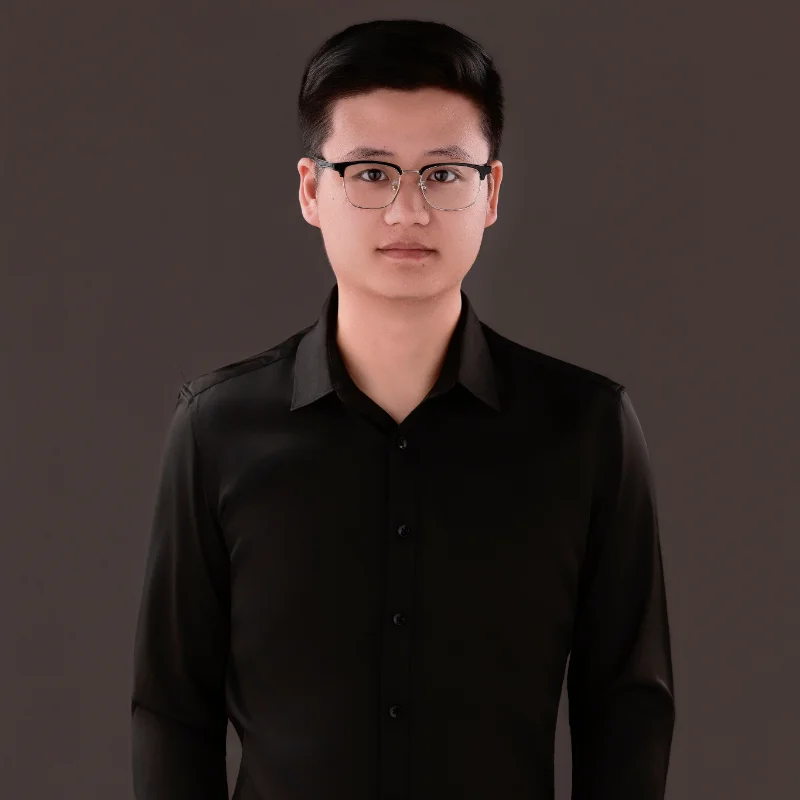 Individual standing in a black button-up shirt against a neutral background.