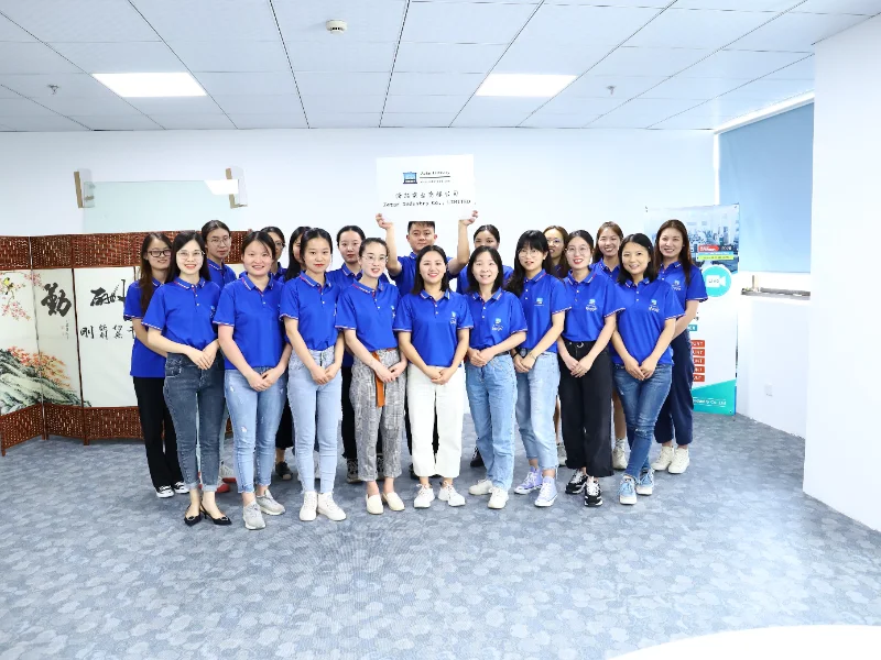 파란색 셔츠를 입은 사람들이 흐릿한 얼굴로 실내에서 포즈를 취하며, 표지판을 들고 함께 서 있는 모습.