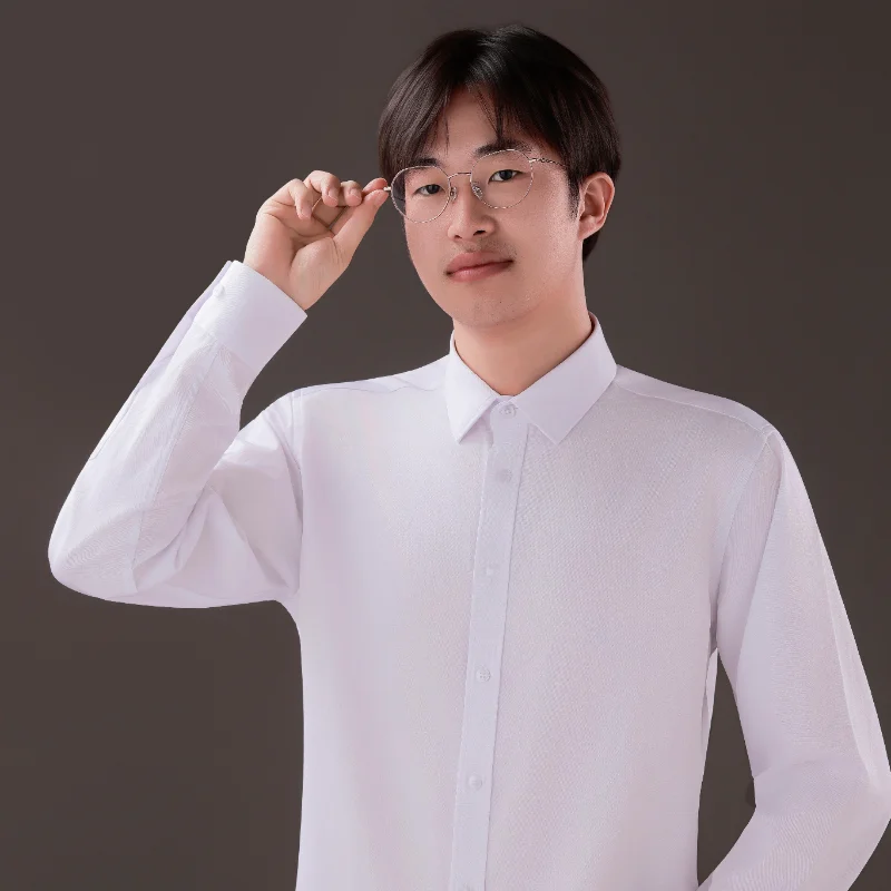 Person wearing a white business casual shirt against a dark background, adjusting glasses.
