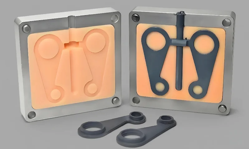 Two parts of a plastic injection mold with molded components displayed in front.