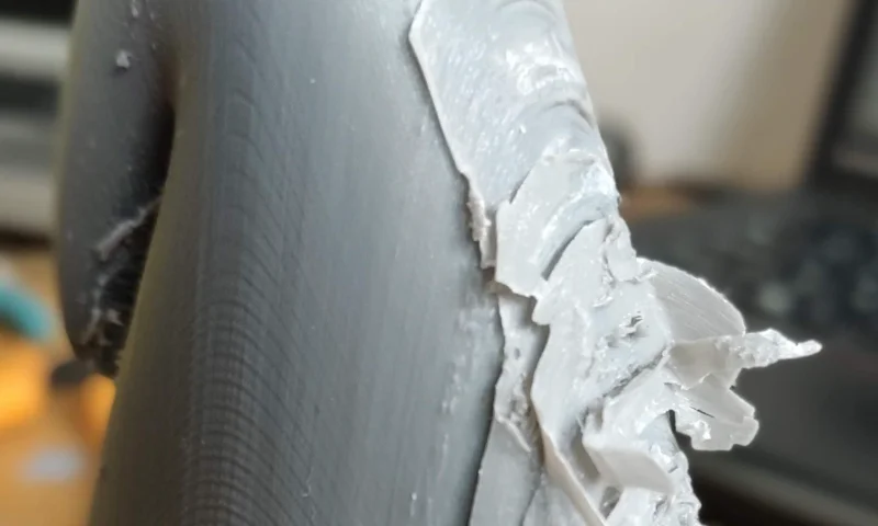 Close-up of a plastic part with visible burrs, highlighting a defect in the injection molding process.