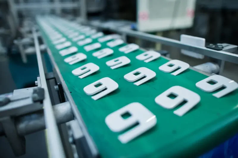 Plastic parts on a green conveyor belt in a molding facility.