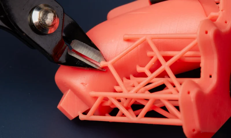 Tool trimming excess sprues from a plastic mold with delicate design.