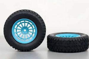 Two black tires with blue rims, one upright and one on its side, on a gray surface.