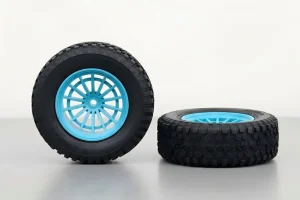 Two black tires with blue rims, one upright and one on its side, on a gray surface.