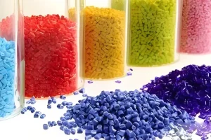 Various colors of plastic pellets in containers and scattered on a surface.
