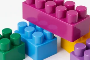 Close-up of colorful plastic building blocks in various colors, including purple, blue, green, and yellow, stacked together.