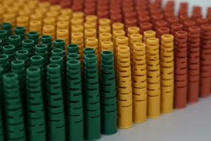 Rows of colorful plastic pieces in green, yellow, and red, showcasing precision injection molding.