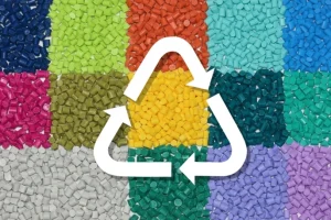 Różnorodne kolorowe granulaty plastiku ułożone w siatce z białym symbolem recyklingu nałożonym na wierzchu, pokazujące temat zrównoważonego rozwoju.