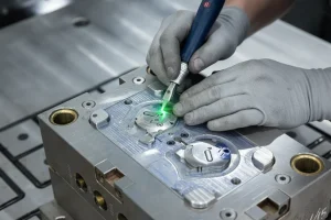 Close-up of a technician using a laser tool on a metal mold, showcasing precision in crafting molds at a plastic injection factory.