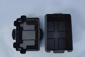 Two black plastic storage box components with compartments, viewed from above on a light background.